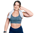 Young hispanic girl wearing sportswear and towel smiling doing phone gesture with hand and fingers like talking on the telephone. communicating concepts.