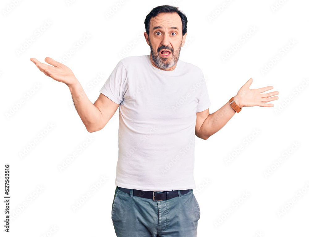 Middle age handsome man wearing casual t-shirt clueless and confused expression with arms and hands raised. doubt concept. Middle age handsome man wearing casual t-shirt clueless and confused expression with arms and hands raised. doubt concept.