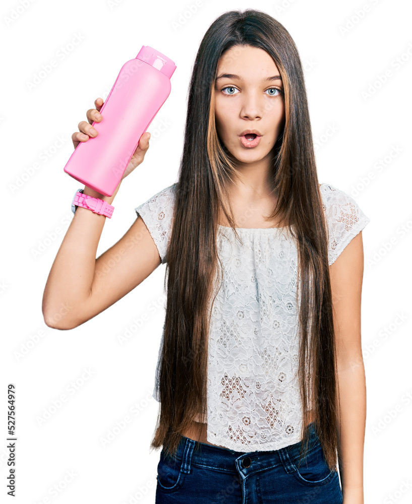 Young brunette girl with long hair holding shampoo bottle scared and amazed with open mouth for surprise, disbelief face Young brunette girl with long hair holding shampoo bottle scared and amazed with open mouth for surprise, disbelief face
