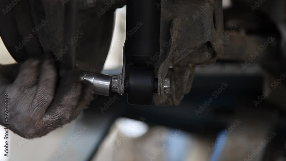 Serviceman checking suspension in a car at garage , process in vintage style