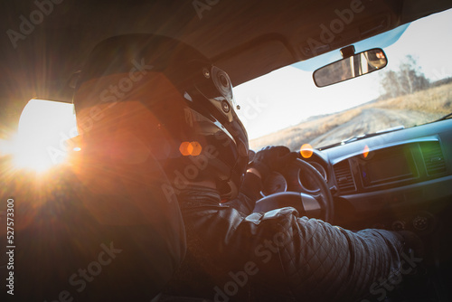 Rally car driver sitting by the steering wheel in the sunset rays concept.