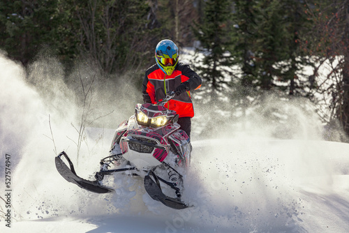 Snowmobile riding with fun in deep snow powder during backcountry tour. Extreme sport adventure, outdoor activity during winter holiday on ski mountain resort