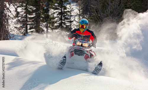 Snowmobile riding with fun in deep snow powder during backcountry tour. Extreme sport adventure, outdoor activity during winter holiday on ski mountain resort