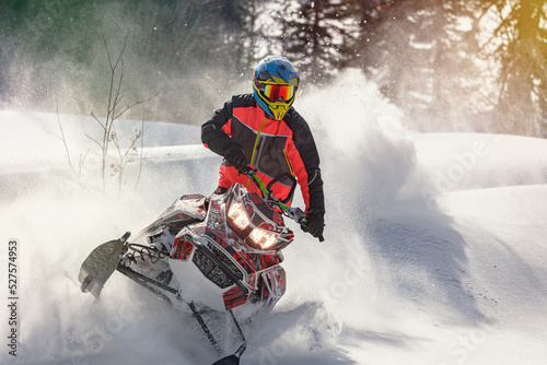 Snowmobile riding with fun in deep snow powder during backcountry tour. Extreme sport adventure, outdoor activity during winter holiday on ski mountain resort