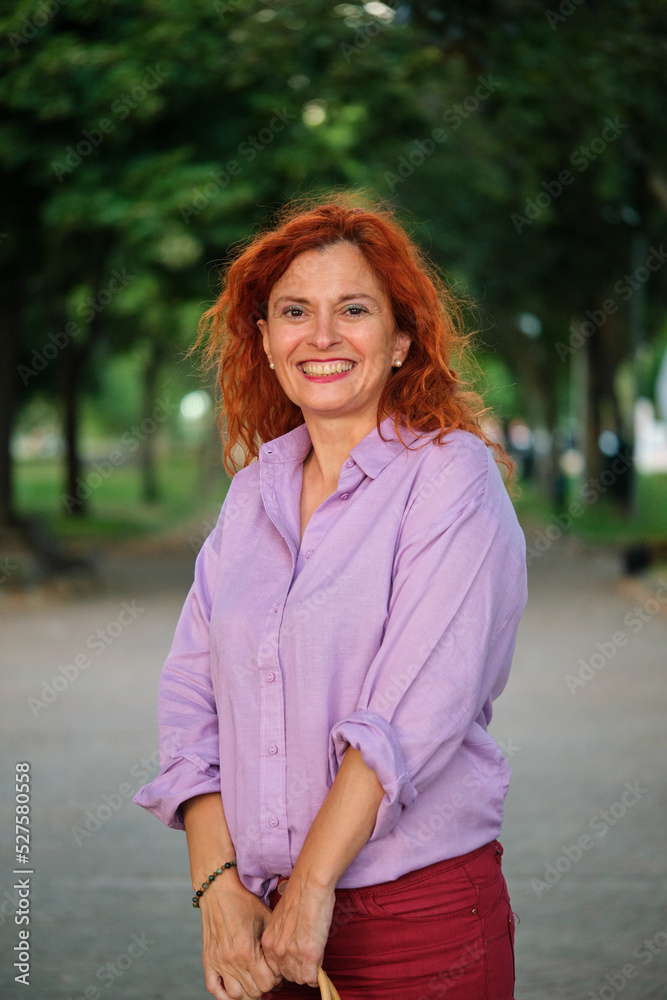 Outdoor portrait of smiling mature redhead woman. Middle aged woman.