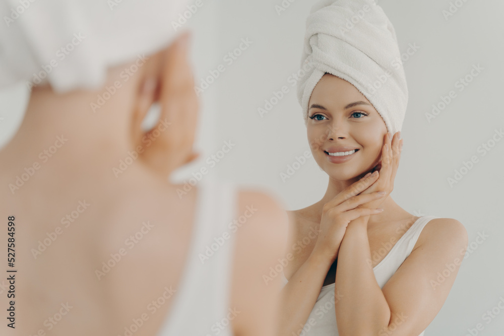 Beautiful happy woman after applying make up looking in mirror and smiling while standing in bathroom Beautiful happy woman after applying make up looking in mirror and smiling while standing in bathroom