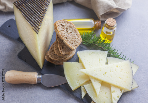 Queso manchego cortado en lonchas y apilado sobre un plato con pan y aceite de oliva