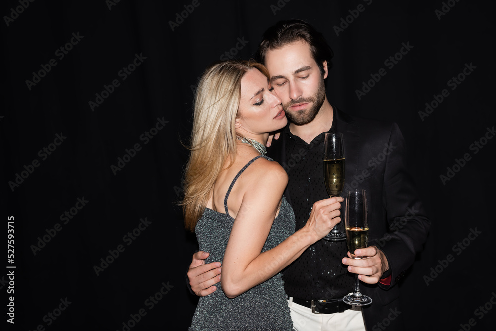 Sexy woman in dress holding glass of champagne and hugging boyfriend isolated on black. Sexy woman in dress holding glass of champagne and hugging boyfriend isolated on black.