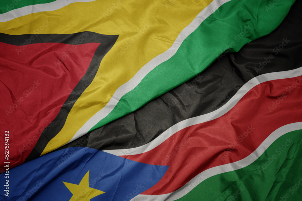 waving colorful flag of south sudan and national flag of guyana.