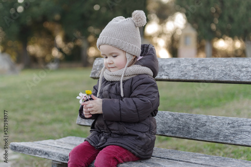 Lovely toddler girl sitting on bench in the park