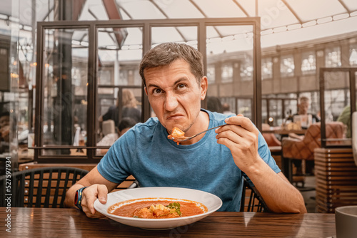 dissatisfied unhappy customer of the restaurant sniffs the disgusting smell of a bowl of soup with spoiled ingredients and is going to complain to the chef