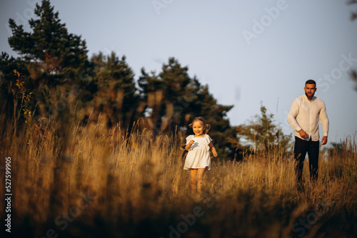 Father with his little daughter running in field
