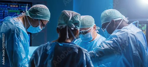 Diverse team of professional medical surgeons perform surgery in the operating room using high-tech equipment. Doctors work to save a patient in a modern hospital. Medicine, technology and healthcare.