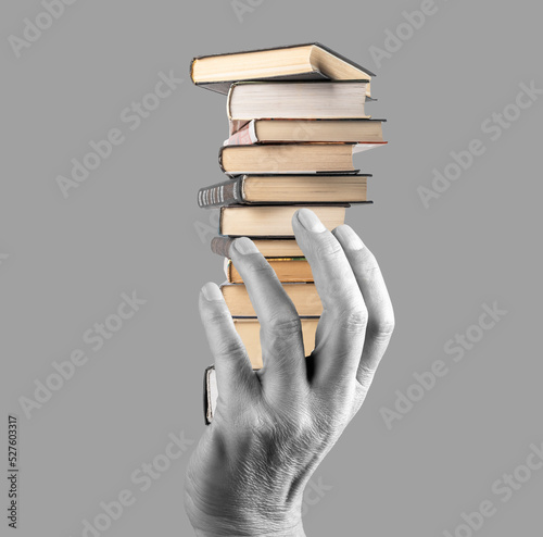 Hand holding books stack on grey background. Knowledge, intellectual development, wisdom, literature importance concept. Black and white photo