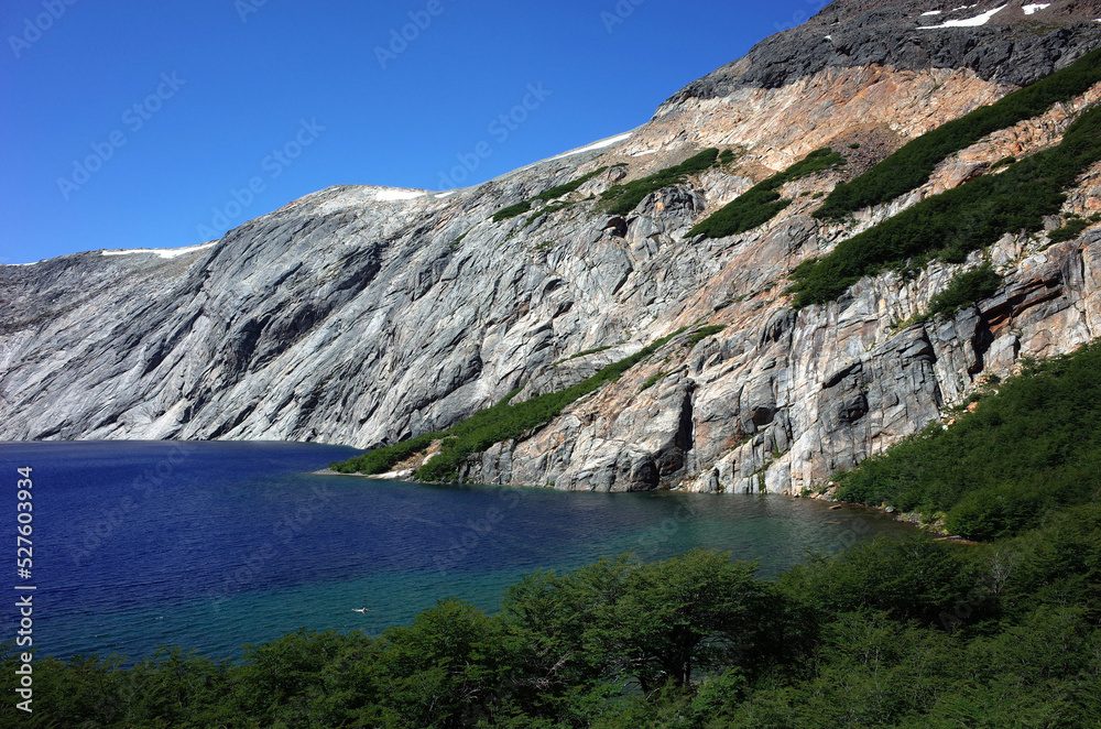 Obraz premium Patagonia nature Alpine lake blue water, Laguna Azul in Nahuel Huapi National Park, Surrounded by granite walls Cerro de las Cristales mountain, Man swimming far on distance, Argentina South America