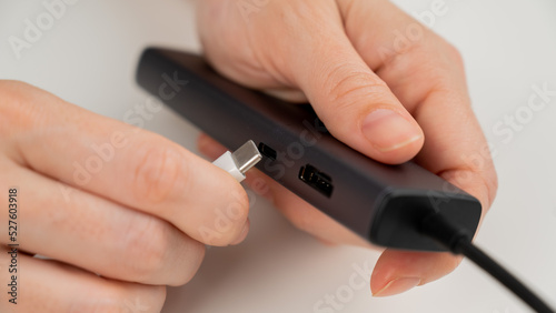 A woman inserts a white Type C cable into a black port.