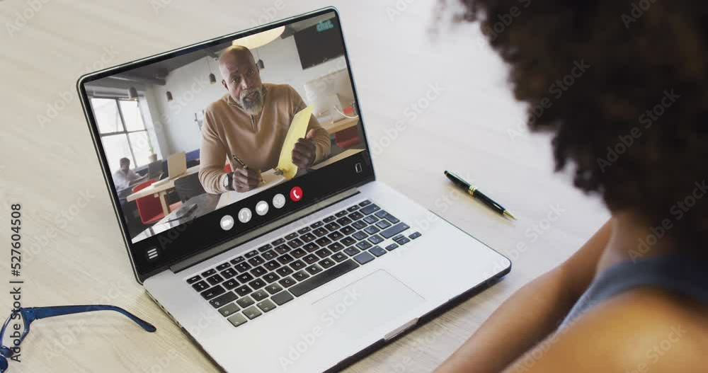 African american woman using laptop for video call, with business colleague on screen