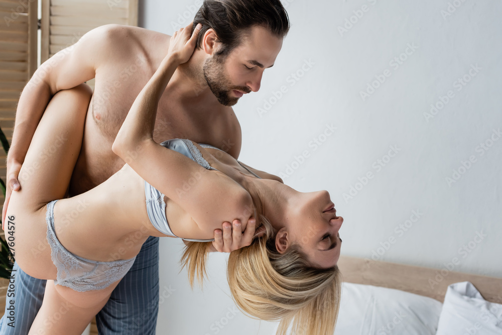 hot woman in sexy underwear near shirtless brunette man in bedroom. hot woman in sexy underwear near shirtless brunette man in bedroom.