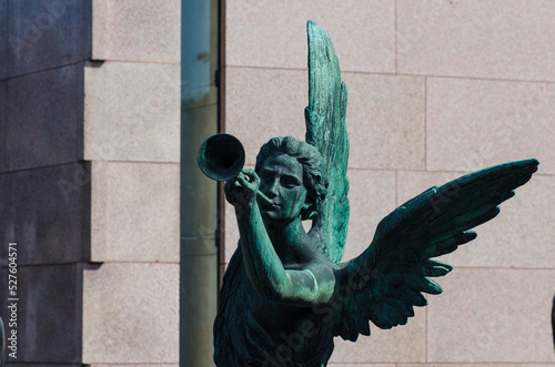 La statua bronzea di un angelo che suona la tromba su una tomba dell cimitero maggiore di Milano photo