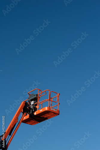 Orange Construction Boom Lift on Blue Sky Background
