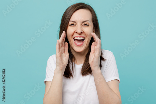 Young promoter expressive caucasian woman 20s she wearing white t-shirt scream hot news about sales discount with hands near mouth isolated on plain pastel light blue cyan background studio portrait.