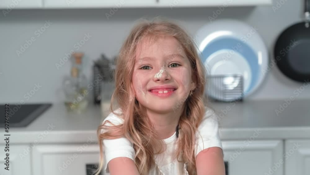 portrait of a charming female child helps mom prepare dough from wheat flour while standing at table in kitchen portrait of a charming female child helps mom prepare dough from wheat flour while standing at table in kitchen