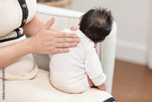 Mother take care her newborn baby hiccups to burp the baby may reduce air in stomach.Newborn baby hiccups after over feeding milk.Newborn Baby Health Care Concept photo