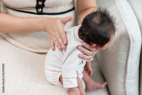 Obraz na płótnie Mother take care her newborn baby hiccups to burp the baby may reduce air in stomach