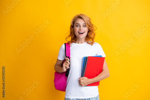 Study, education, university, college concept on yellow background. Portrait of beautiful smiling woman student with backpack and notes book.