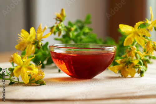 Red oil made from St. John's wort flowers in a bowl on a table