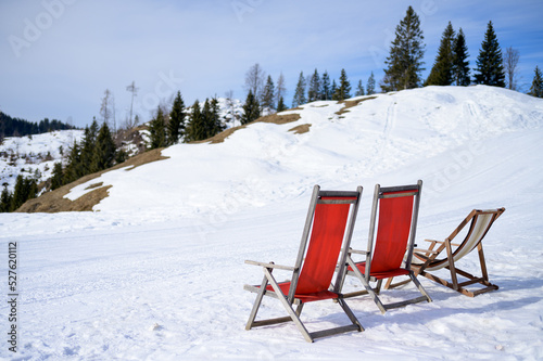 Two red chairs standing in the snow