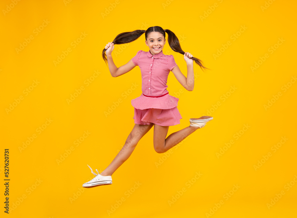 Excited teenager. Full length funny teenager kid jump enjoy rejoice win isolated on yellow background. Small child girl in dress jumping. Excited teenager. Full length funny teenager kid jump enjoy rejoice win isolated on yellow background. Small child girl in dress jumping.