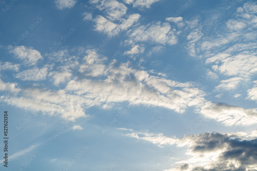 a view of a beautiful blue sky with white puffy clouds converging in perspective, the sun is setting behind the clouds, the photo was taken in the summer before sunset a view of a beautiful blue sky with white puffy clouds converging in perspective, the sun is setting behind the clouds, the photo was taken in the summer before sunset