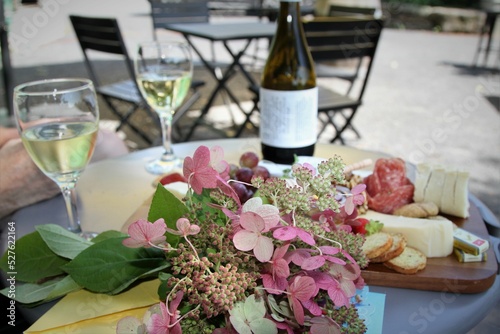 Gtazing board with assorted cheeses, meats, crackers, wne and bouquet of flowers for outdoor dining photo