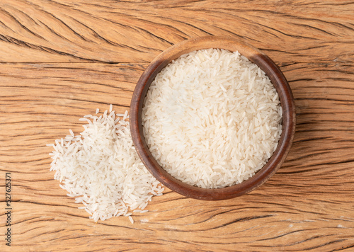Raw white rice in a bowl over wooden table