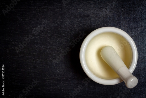 White ceramic mortar and pestle on black rustic wooden background, top view.