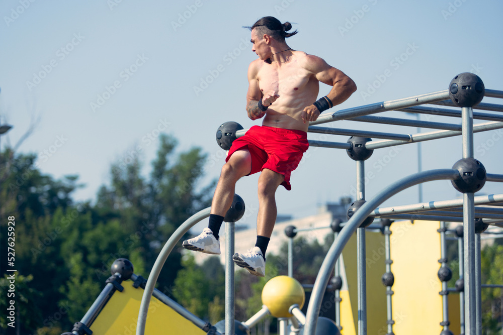 Obraz premium Lifestyle portrait of athlete, muscular shirtless man workout at sports ground at public park in summer morning, outdoors. Action, skills, challenges
