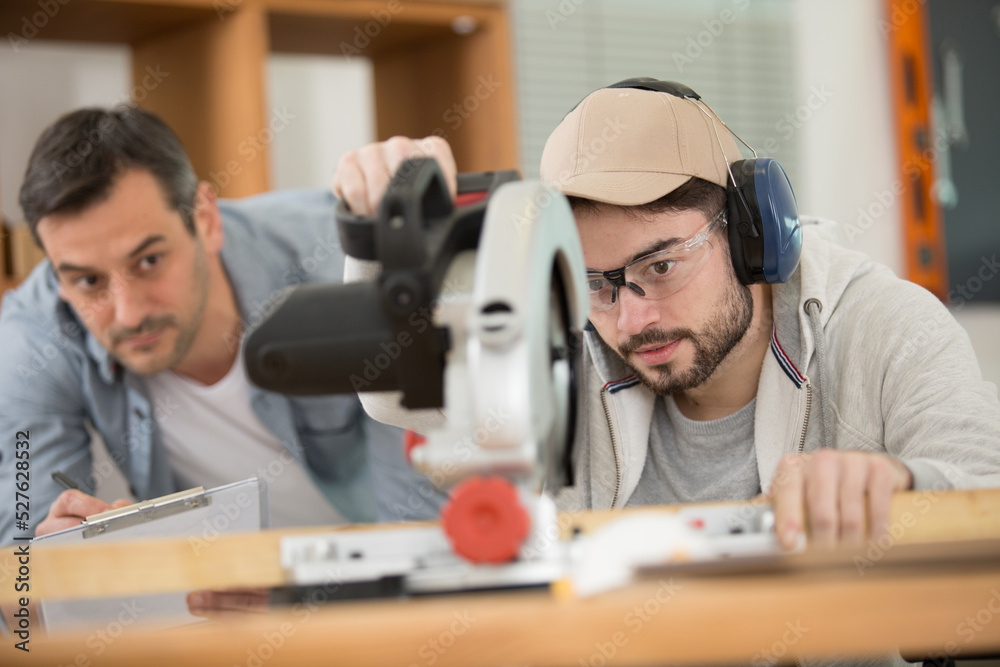 supervisor assessing student using a circular saw