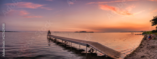 Sunset with children playing on a pier at Faldsled campin on Funen, Denmark photo