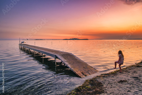 Sunset with children playing on a pier at Faldsled campin on Funen, Denmark photo