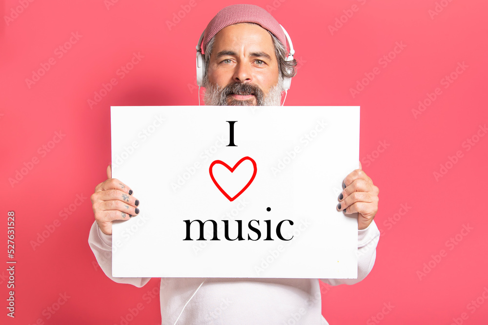 Mature modern man with headphones holding a sign with i love music text.