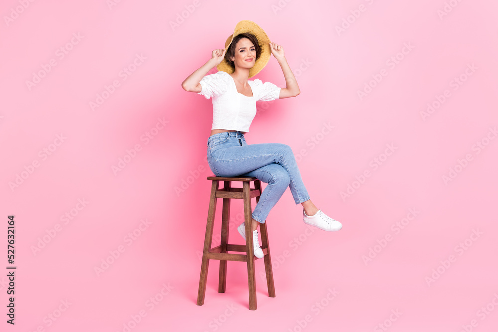 Full length photo of adorable pretty lady wear white crop top cap sitting wooden chair beach bar isolated pink color background Full length photo of adorable pretty lady wear white crop top cap sitting wooden chair beach bar isolated pink color background