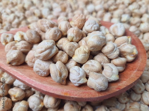 Chickpeas (Cicer arietinum) closeup in a wooden spoon, blurred background, selective focus. It is also known by the names: Gravanço, Herbanzo, Chicken Pea or Bengal Pea or Duck Grain. photo