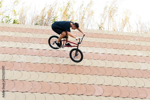 Young male riding BMX bike down slope photo