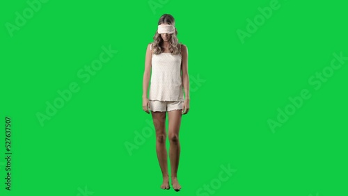 Sleep walking young woman in pajamas with eyes covered by sleep mask. Full body isolated on green screen background photo