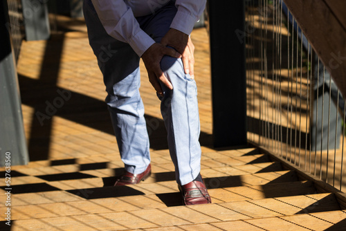 Senior adult having knee pain while climbing up stairs