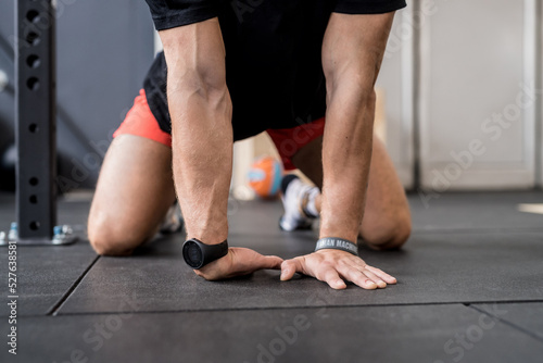 Close up unrecognizable man stretching indoor gym wearing fitness smartwatch
