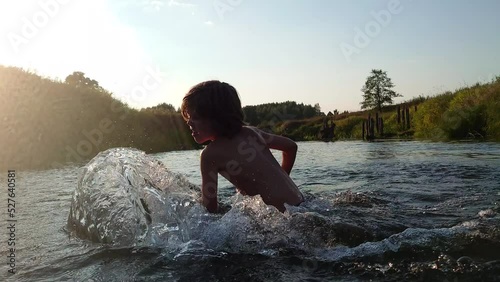 Child playing in the water. Kid swimming in the river and making big splash. Happy summer holidays.