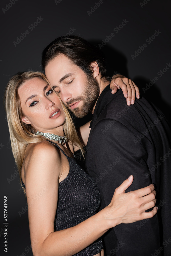 Seductive blonde woman hugging boyfriend in jacket on black background. Seductive blonde woman hugging boyfriend in jacket on black background.