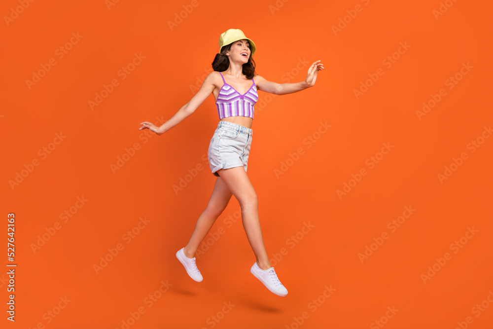 Full length photo of sweet shiny woman dressed violet bra jumping high walking empty space isolated orange color background Full length photo of sweet shiny woman dressed violet bra jumping high walking empty space isolated orange color background